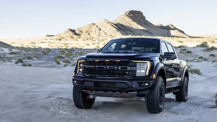 The 2023 Ford F-150 Raptor R sits parked in the desert. The truck is black. We see it from a front quarter angle, facing slightly to our left.
