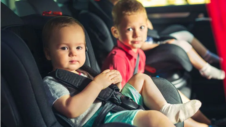 Three Kids Traveling In Car Seats