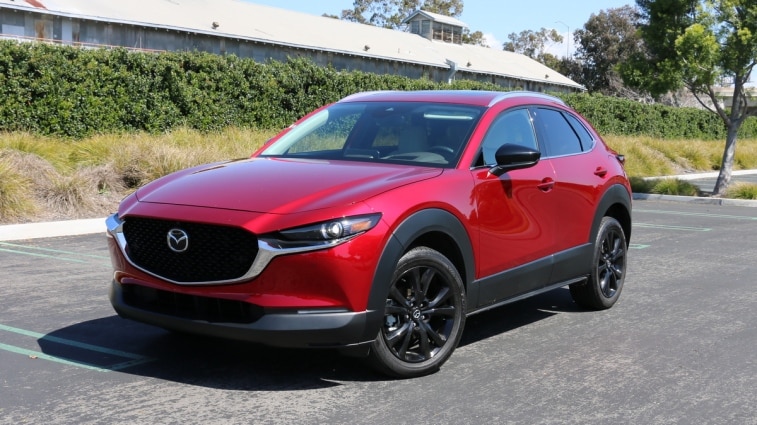 Red 2023 Mazda CX-30 with a green hedge in the background.