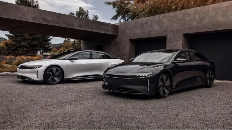 A pair of 2022 Lucid Air sedans with the Stealth Look package. One is white, one black. Both have darkened trim. We see them from a front quarter angle