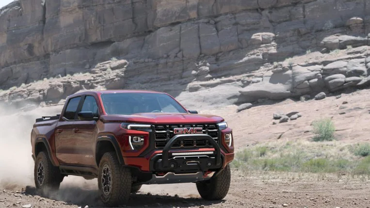 The 2023 GMC Canyon AT4X off-road model, in red, seen driving through -- you guessed it -- a canyon.