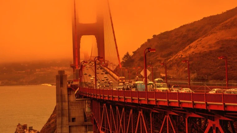 Traffic crossing the Golden Gate bridge. The sky is orange due to wildfire smoke.